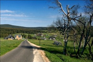 Panoramatický pohled na osadu Jizerka v létě s okolními kopci Jizerských hor